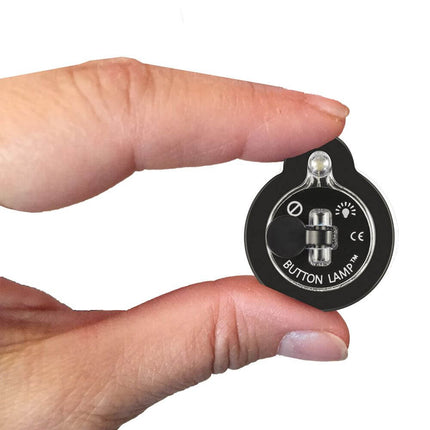 Two fingers holding a button lamp to show relative size