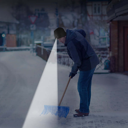 Person using the PowerCap beanie to see while shoveling snow