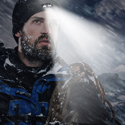 Man covered in snow using dual lighted beanie to help see