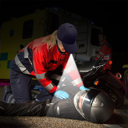 EMT wearing an LED headlamp hat helping an injured motorcyclist 