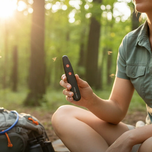 Person using a rechargeable insect bite relief device in a forest setting with 'Sting Stick' branding.