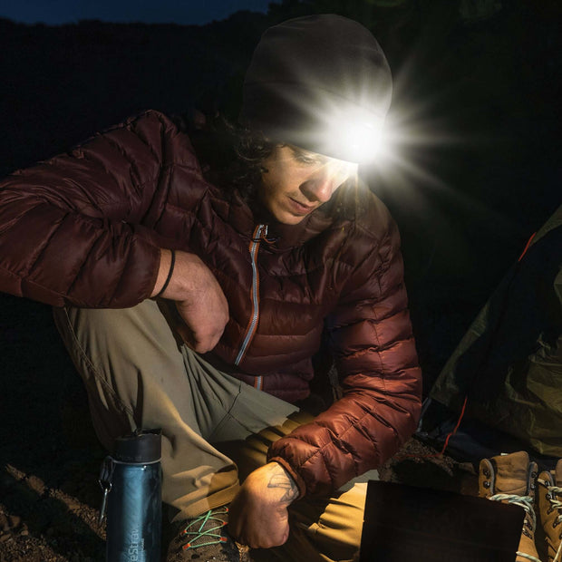 Man camping wearing a LED headlamp beanie