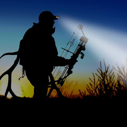 Hunter with crossbow using lighted cap in the early morning