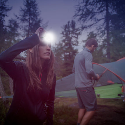 couple camping in the woods with a rechargeable LED headlamp