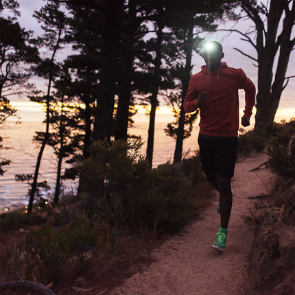 runner in the mountains by the ocean wearing a rechargeable LED headlamp