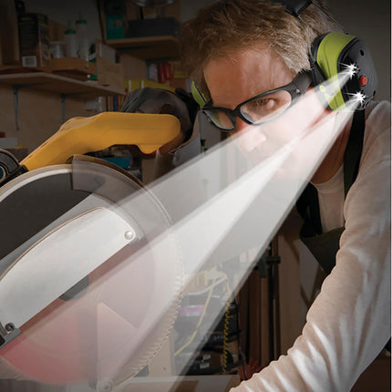 man using a power saw for a DIY project wearing LED lighted earmuffs