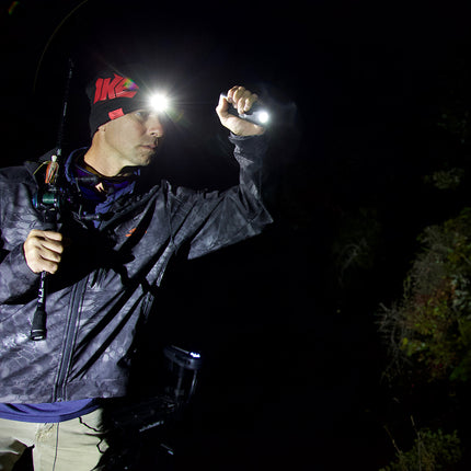 fisherman holding a flashlight and wearing an LED lighted headlamp beanie