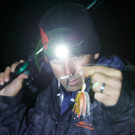man looking at fishing tackle wearing an LED lighted headlamp beanie