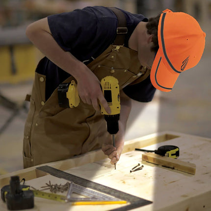 man wearing an orange POWERCAP 25/10 LED lighted safety hat while using a hand drill