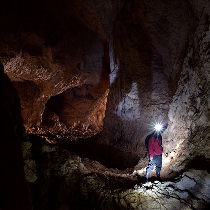 man wearing a POWERCAP 25/75 solar microfiber LED lighted hat and exploring a cave