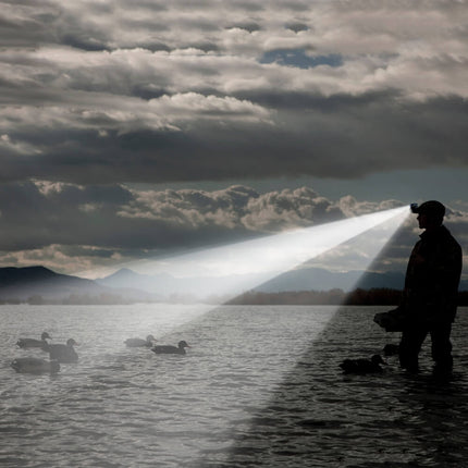Man wearing a POWERCAP EXP 200 LED lighted headlamp hat wading in a lake surrounded by ducks