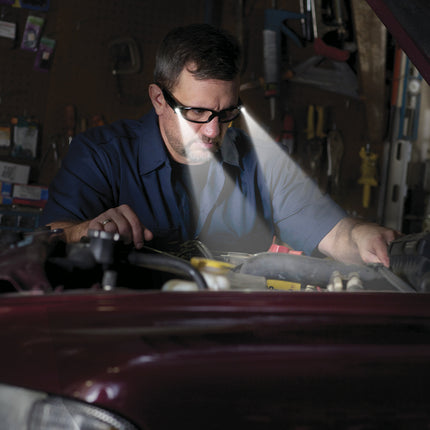 mechanic looking at a car in a garage wearing LED safety glasses